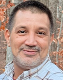 Portrait of William 'Billy' Christian smiling outdoors amidst autumn foliage, showcasing a warm and approachable demeanor.