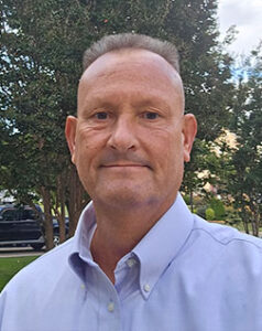 Barry Winebarger - Portrait, professional headshot with a light blue shirt and natural background, smiling slightly- Page Barry Winebarger.